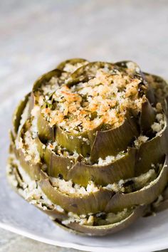 an artichoke dish on a white plate topped with rice and parmesan cheese