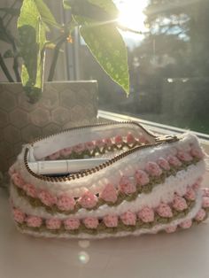 two purses sitting on top of a table next to a potted plant in front of a window