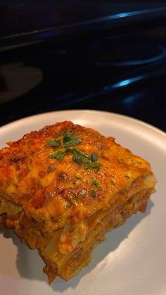 a white plate topped with lasagna covered in cheese and sauce on top of a stove