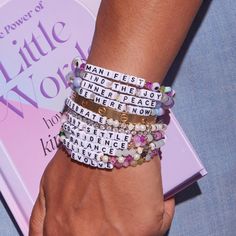 a close up of a person's hand wearing bracelets with words on them