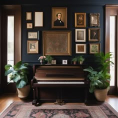 a piano in a room with many framed pictures on the wall and plants next to it