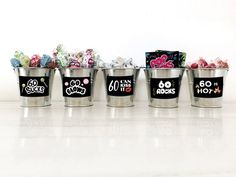 four buckets filled with candy sitting on top of a white counter next to each other