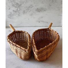 two wicker baskets sitting next to each other on a white counter top with marble background