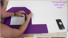 a woman is working on a piece of paper with purple and white accents, including a cell phone