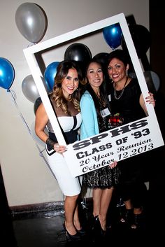 two women holding up a sign with balloons in the background that says class of 2013