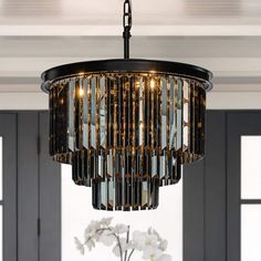 a chandelier hanging from the ceiling in a dining room with white flowers and windows