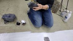 a person sitting on the ground with some tools in front of her and one hand holding something