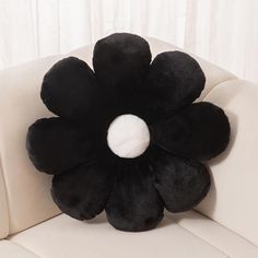 a black flower pillow sitting on top of a white couch