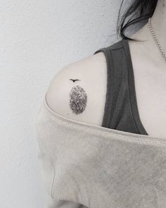 a woman with a tattoo on her shoulder has a small pine tree in the middle