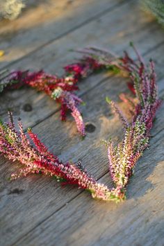 a heart shaped wreath made out of flowers on a wooden table with the word love spelled in it