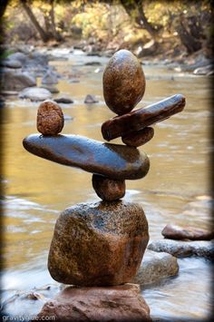 rocks stacked on top of each other in front of a river