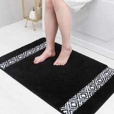 a woman is standing on a black rug in the bathroom with her bare feet sticking out