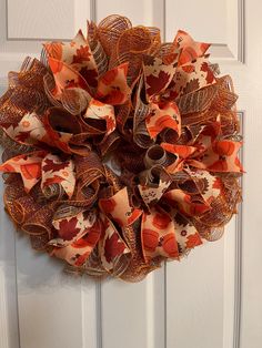 an orange and brown wreath hanging on the front door