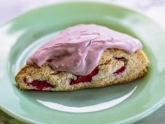 a scone with pink icing on a green plate