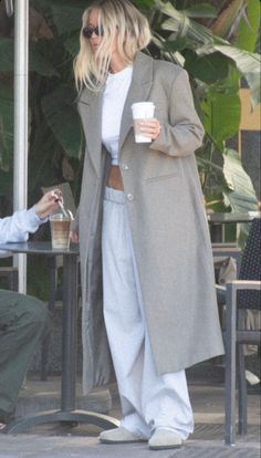 a woman standing next to a man holding a coffee cup and talking on a cell phone