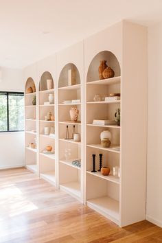 a room filled with lots of white bookshelves and vases on top of them