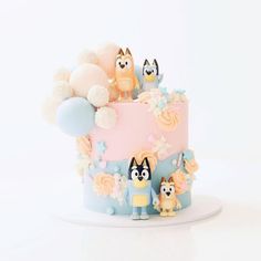 a cake decorated with animals and balloons on a white tableclothed surface in front of a white background