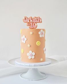 there is a pink cake with flowers on it and a name topper in the middle