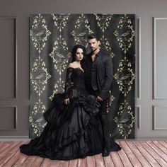 a man and woman dressed in black standing next to each other on a wooden floor