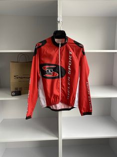 a red jacket hanging on a white shelf