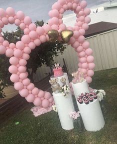 a heart shaped balloon arch with cupcakes and pink frosting on the top