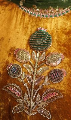 a close up view of a gold velvet dress with flowers on the front and side