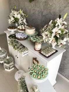 a table topped with cakes and cupcakes covered in frosting next to flowers