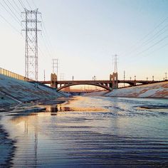 a bridge over a river with power lines above it and snow on the ground below