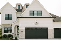 a white house with black garage doors and windows