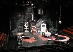 an empty stage with chairs, tables and stairs on it's sides in the dark