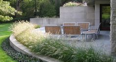 an outdoor dining area with chairs and table surrounded by tall grass in the foreground