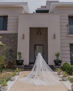 a bride's veil is draped over her wedding dress in front of a house