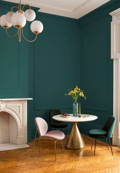 a dining room with green walls and gold accents, including a table that has two chairs around it