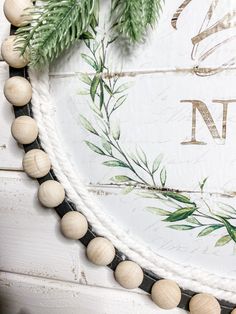 a close up of a wreath on a wall with pine needles and balls hanging from it