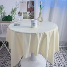 a round table with a white cloth on it and a potted plant next to it