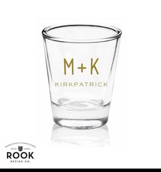 a shot glass with the word m + k in gold on it and an image of a