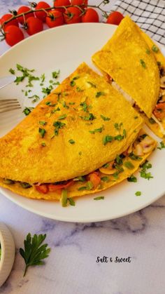 an omelet is sitting on a white plate next to some tomatoes and parsley