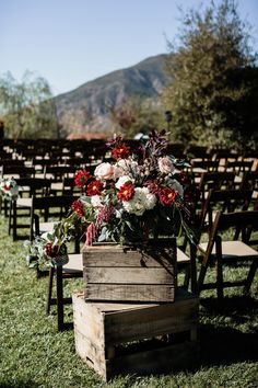 a wooden box with flowers on it sitting in the grass next to an empty chair