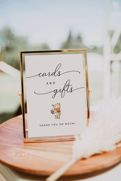 a card that says cards and gifts on top of a wooden table next to a white feather