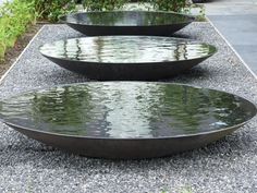 three metal bowls sitting on top of gravel