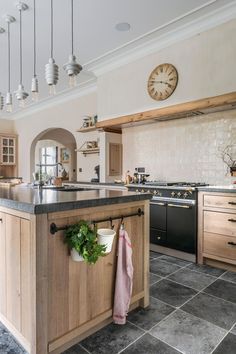 a large kitchen with an island in the middle and a clock on the wall above it