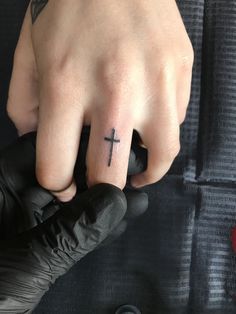 a person with a cross tattoo on their ring finger