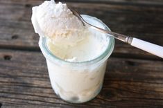 there is a spoon that is in a glass with some ice cream on the table