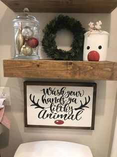 a toilet in a bathroom next to a wooden shelf with a christmas sign on it