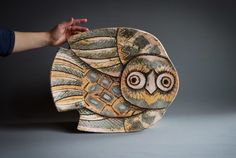 a hand is holding an owl shaped object