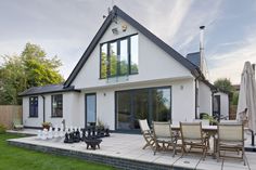 a white house with chess set outside on the lawn and in front of it is an umbrella