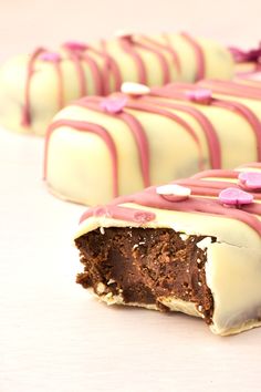 several pieces of chocolate cake with pink and white icing on them, sitting next to each other