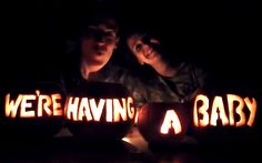 two people sitting in front of carved pumpkins with words reading we're having a baby