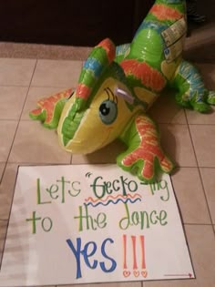 a stuffed animal laying on the floor next to a sign that says let's go to the dance yes