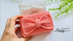 a hand holding a small crocheted bow on top of a table